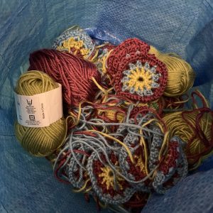 a bag of yarn and crochet circles waiting to be transformed into a sunburst granny blanket