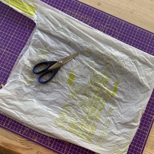 a grey carrier bag and some scissors on a cutting mat ready for making plarn
