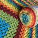 Lockdown blanket dilemma: a new ball of rainbow yarn on top of a crocheted blanket